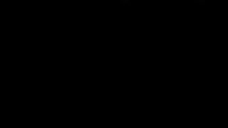 Performer lying on a padded table in a dim studio room